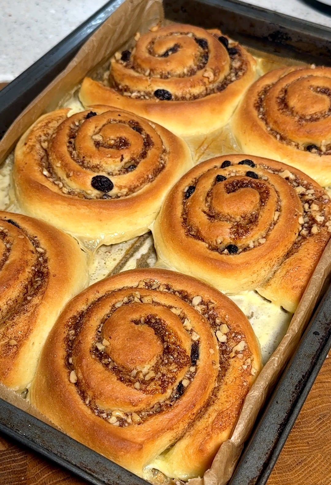 Golden brown walnut cinnamon rolls baking in the oven, filling the kitchen with a warm, sweet aroma.