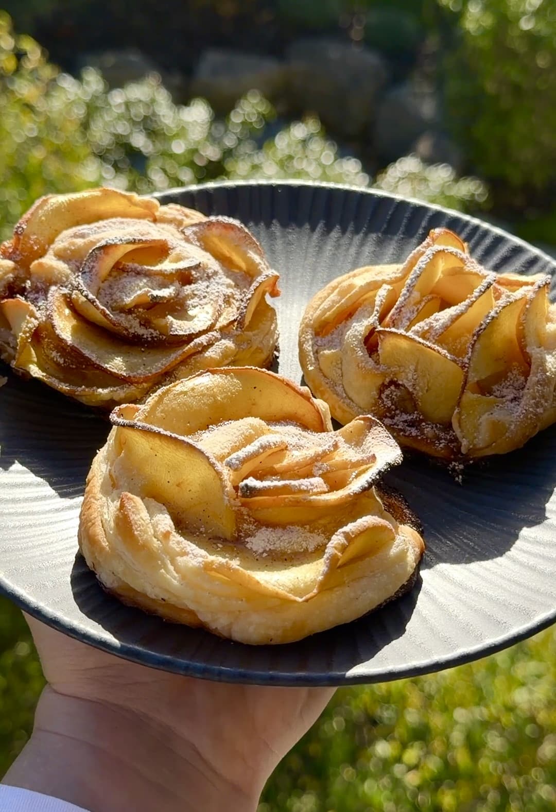 Close-up of apple roses with crisp puff pastry petals and soft baked apples, lightly sprinkled with sugar, ready to serve.
