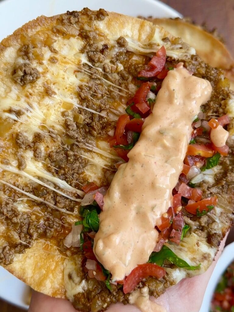 rispy folded beef tacos topped with fresh salsa and drizzled with creamy sauce, ready to serve.