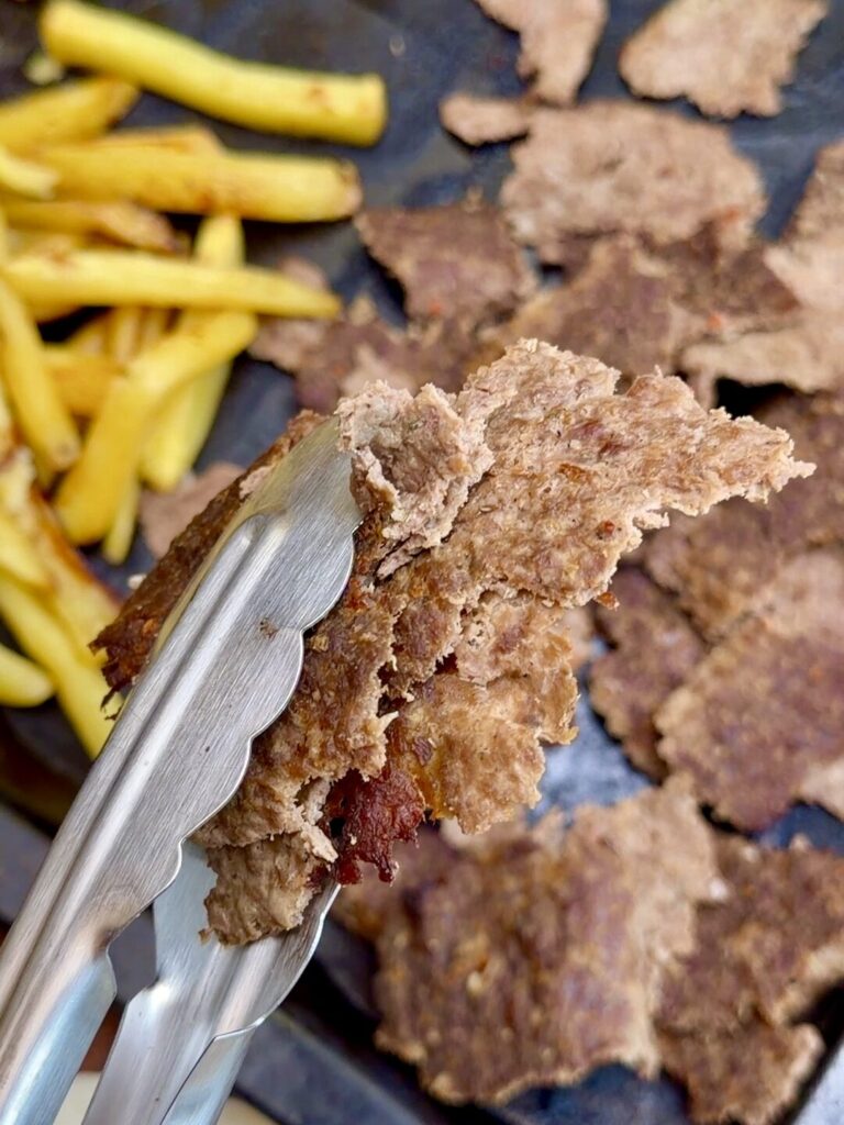 Thin pieces of cooked döner kebab held in tongs