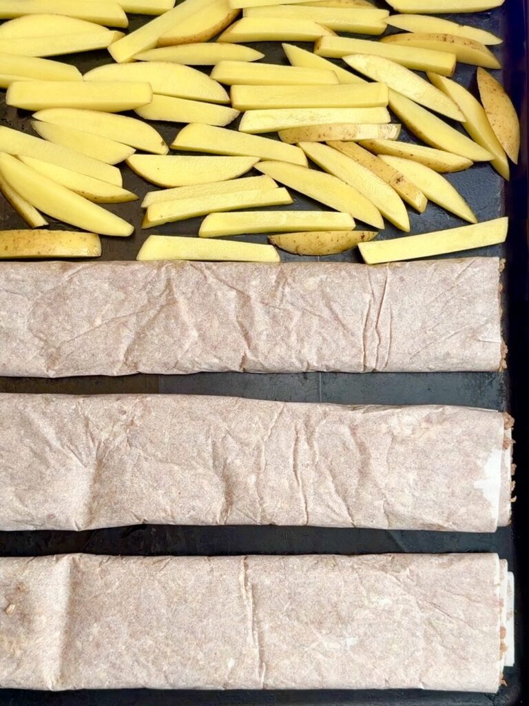 Rolled döner kebab logs placed on a baking tray ready for the oven