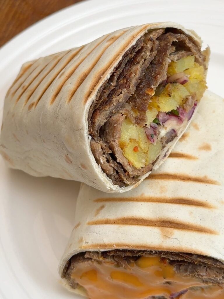 Wrap filled with oven-style döner kebab, crispy fries, and sumac-spiced onions