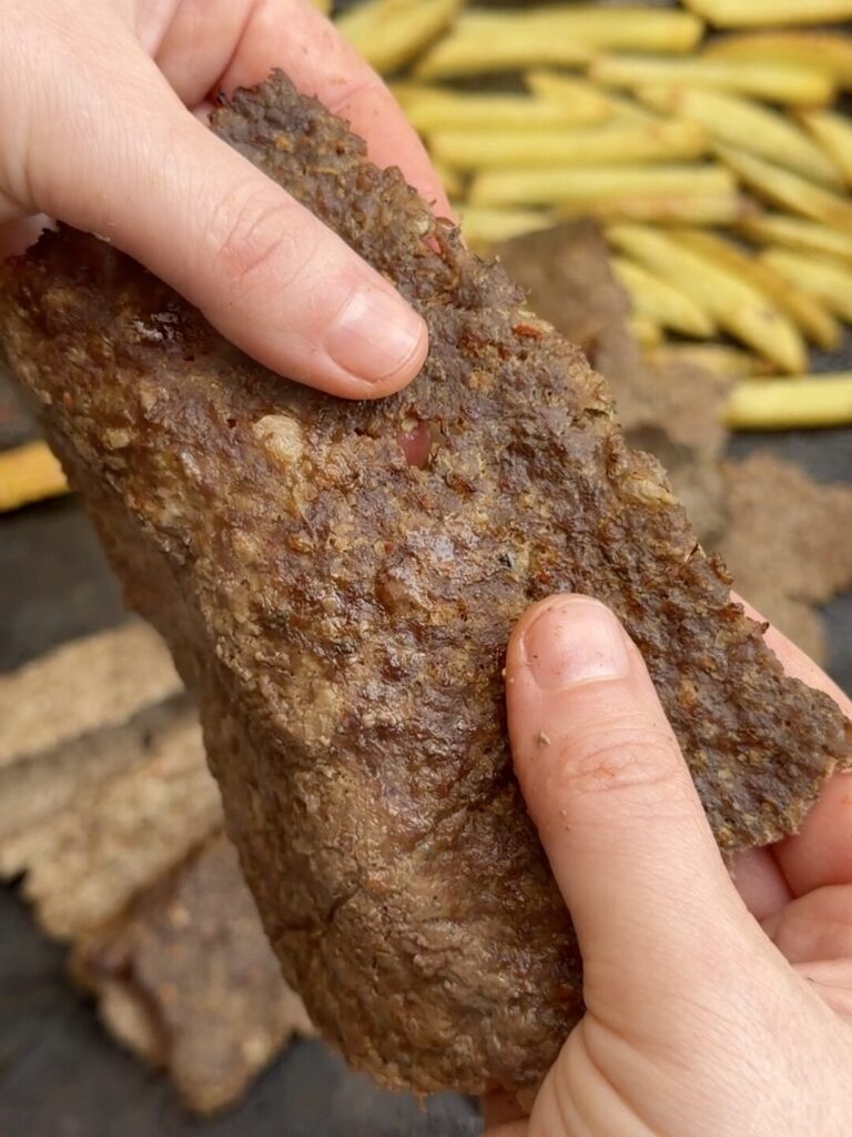 Breaking cooked döner kebab into thin, bite-sized pieces by hand