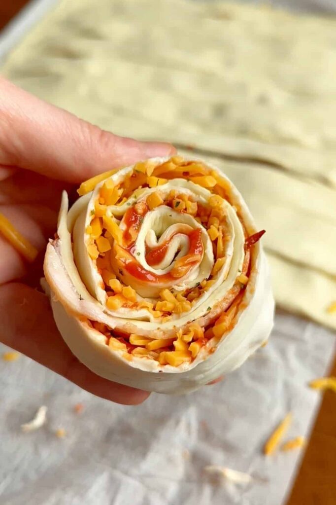 A single puff pastry roll held in hand, showing its tight spiral shape.