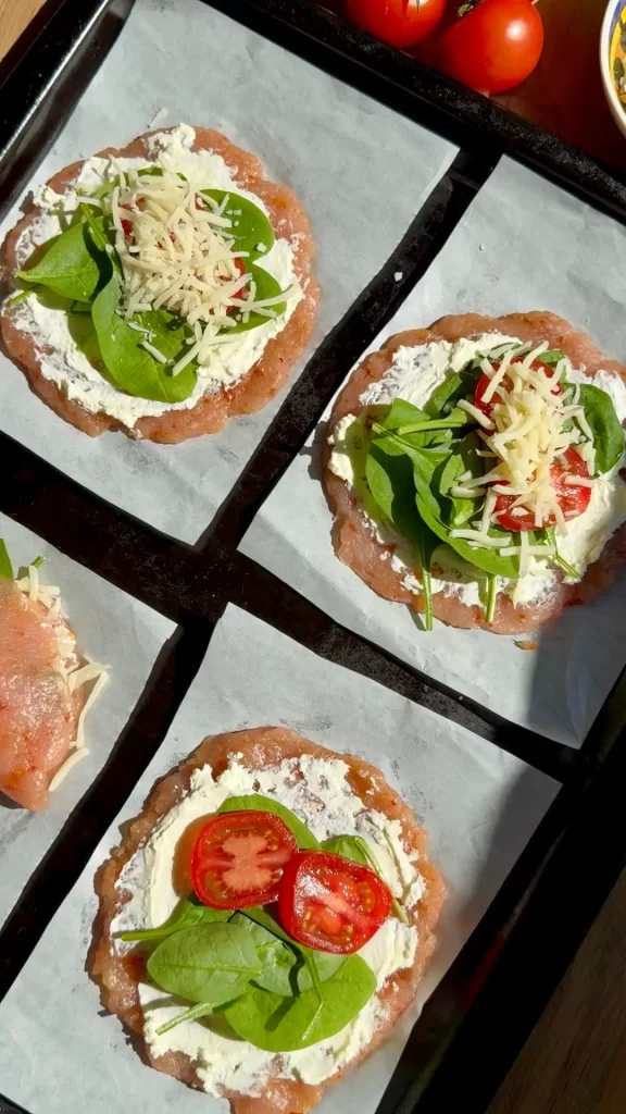 Cream cheese spread on chicken disc topped with spinach, sliced tomato, and mozzarella for baked stuffed pockets filling